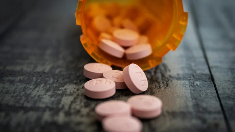 A prescription vial with tablets spilled on a counter
